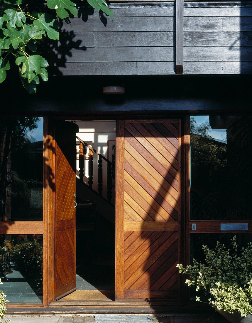 Wooden entry door with open door and view of a stairway