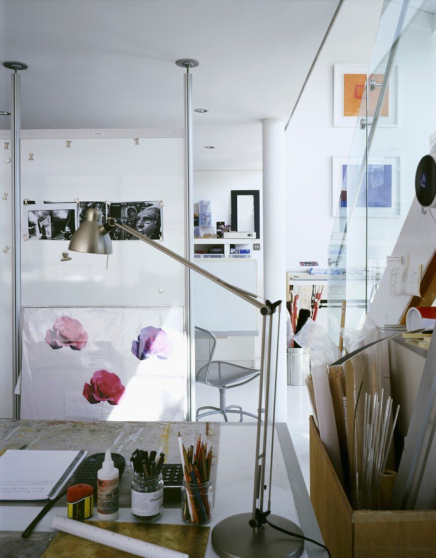 Arbeitsplatz eines Künstlers oder Architekten mit Schreibtischlampe aus Edelstahl neben Modellbaumaterialien