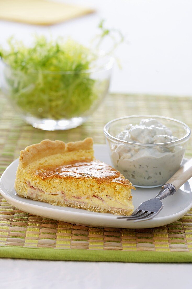 Ein Stück Quiche Lorraine mit Quarkdip