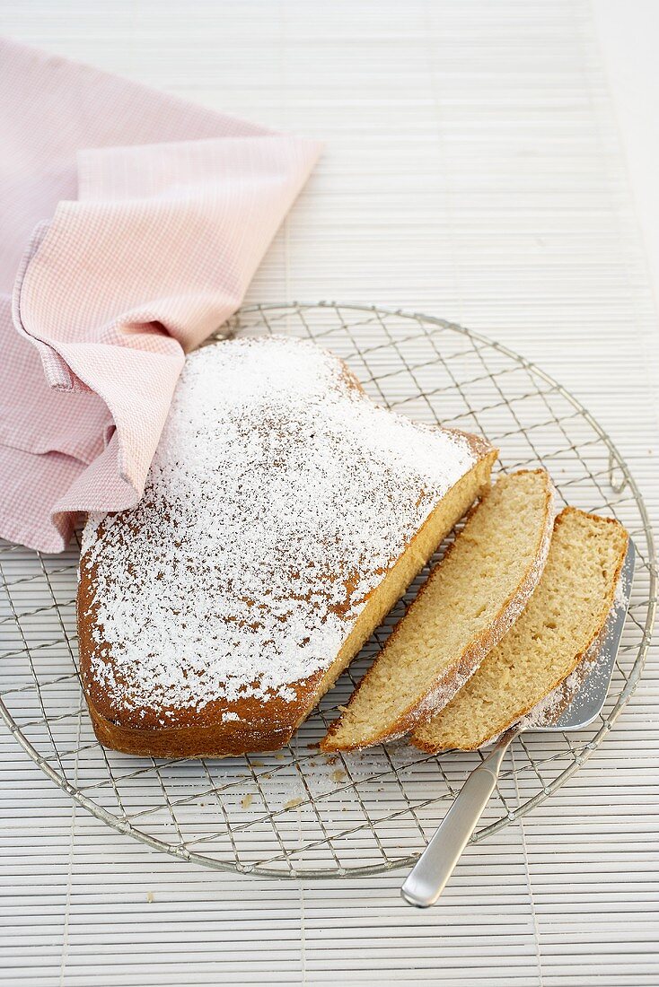 A heart shaped sponge cake dusted with icing sugar, sliced