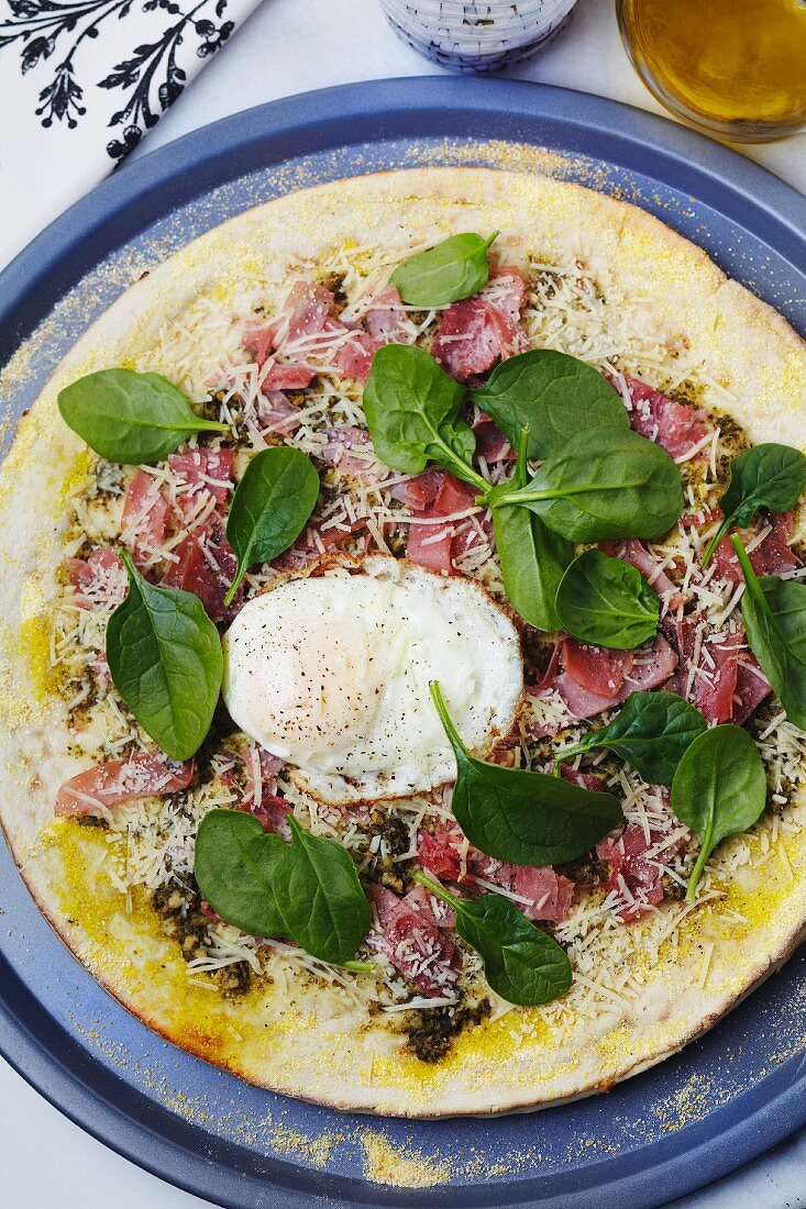 Pizza Topped with Prosciutto, Spinach, Fried Egg and Olive Oil