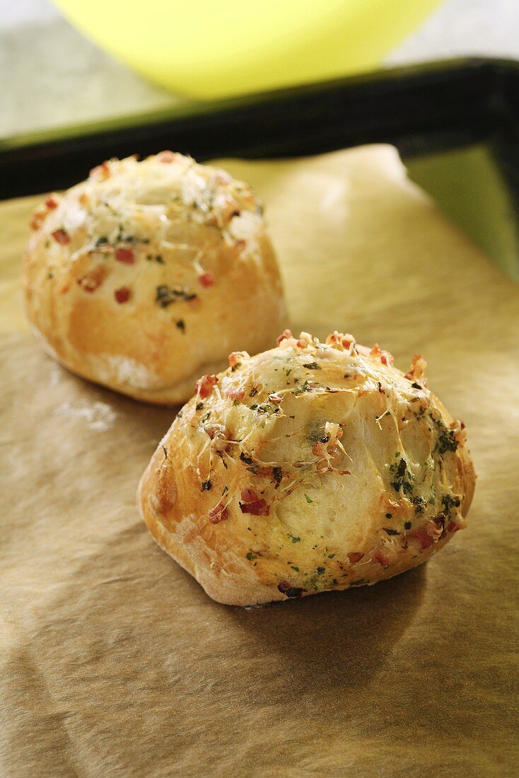Freshly baked cheese rolls with bacon and herbs on a baking tray