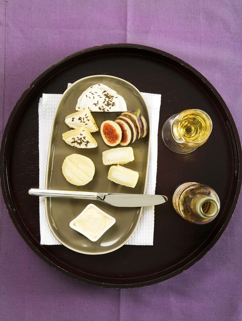 A cheese platter (Harz, Munster, Romadur, Limburg) with figs and white wine