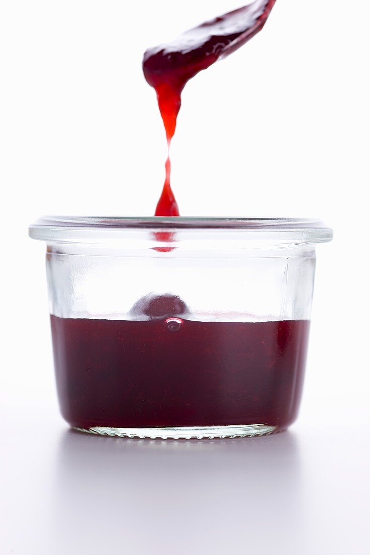 Jam dripping from the spoon into a jar