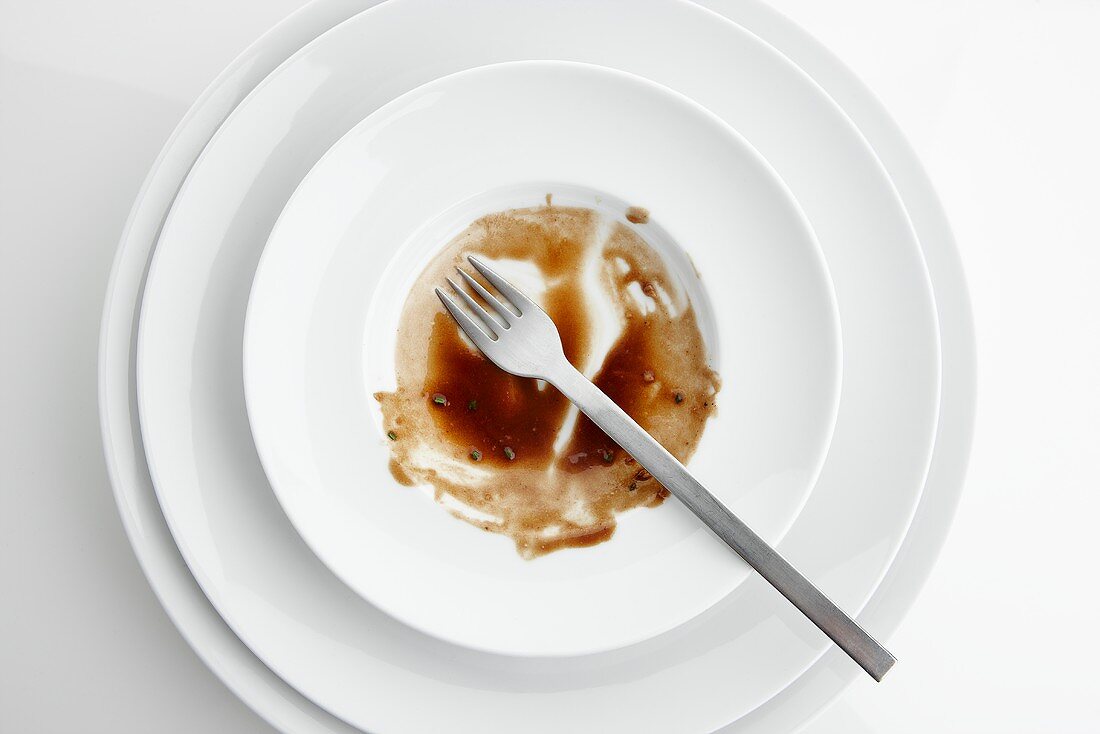 The remains of sauce and a fork on a plate seen from above