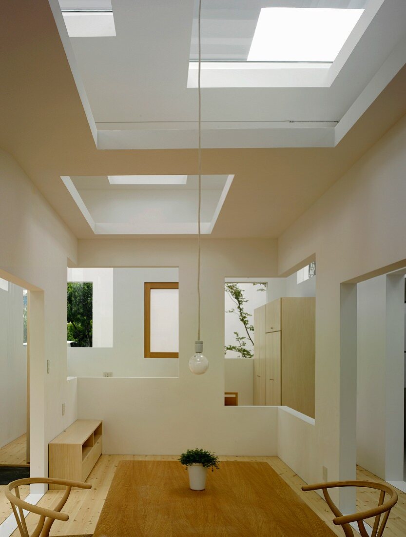 Simple table and chairs in Bauhaus style in a modern house with cut-outs in the wall and ceiling