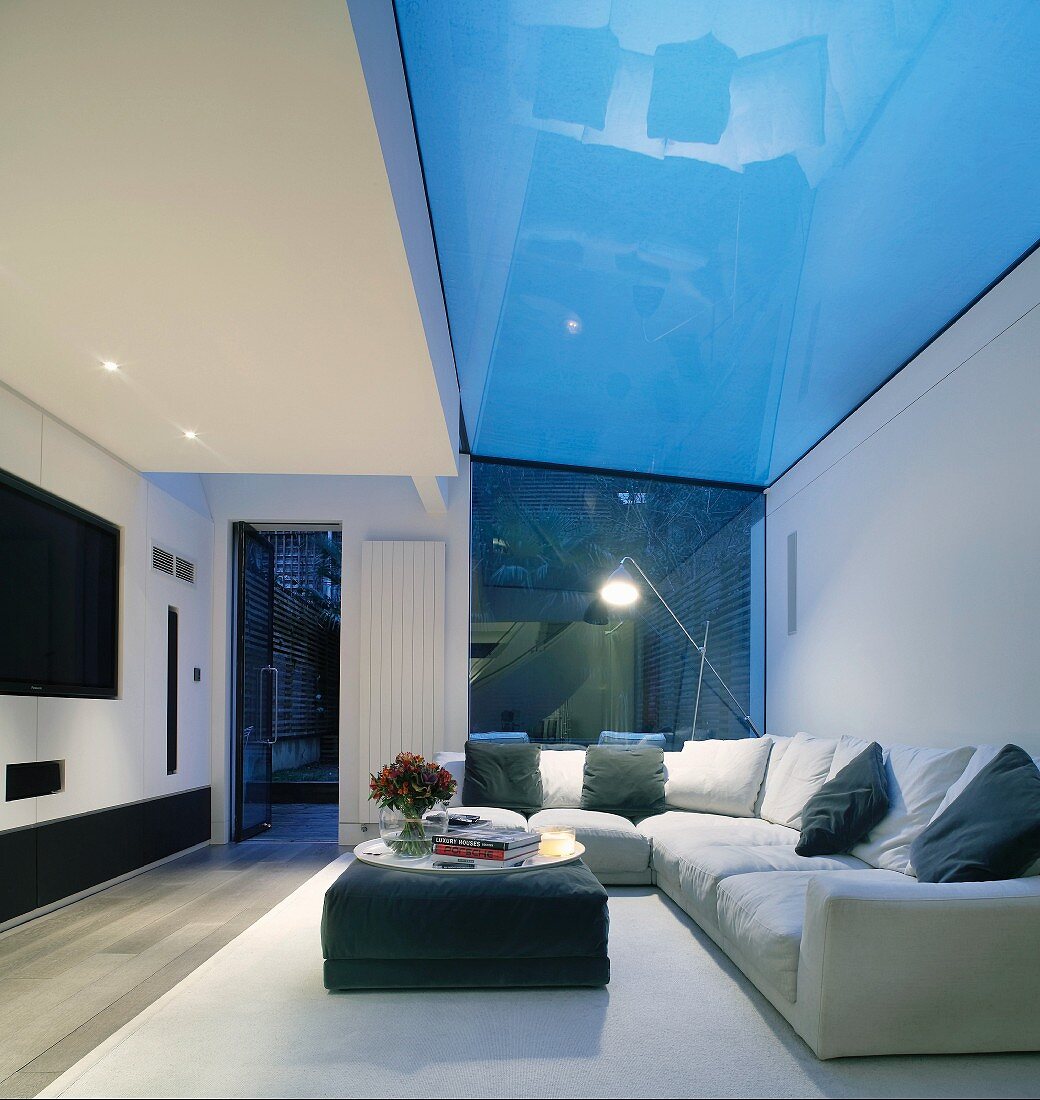 Gemütliche Polstersofaecke mit Kissen im modernen Wohnraum mit verglastem Deckenbereich