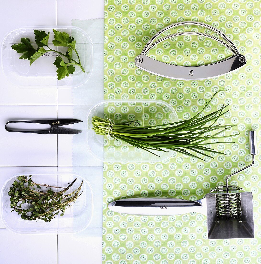 Fresh herbs, a chopping knife, herb scissors and a herb mill