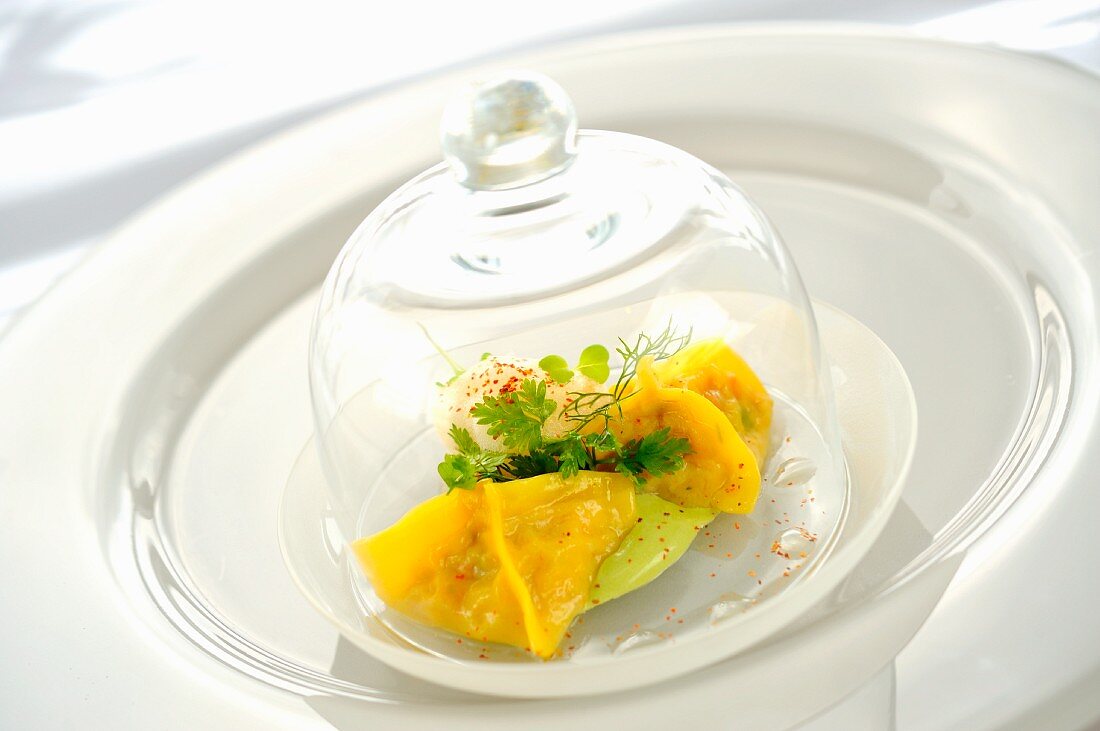 Ravioli filled with king crab under a glass cloche on a glass plate