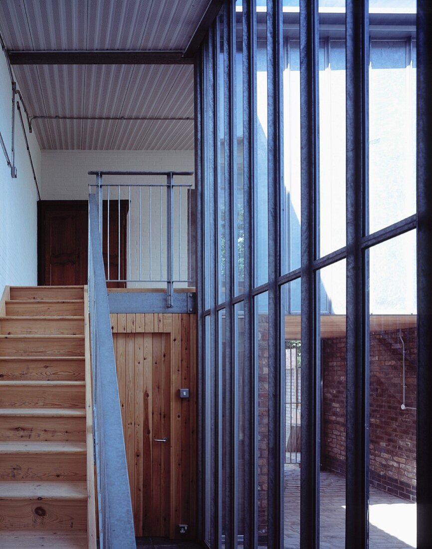 Stairway with rustic, wooden stairway in front of a glass and steel facade