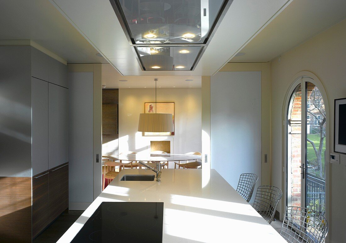 Modern kitchen unit in front of open sliding doors with a view of a dining table