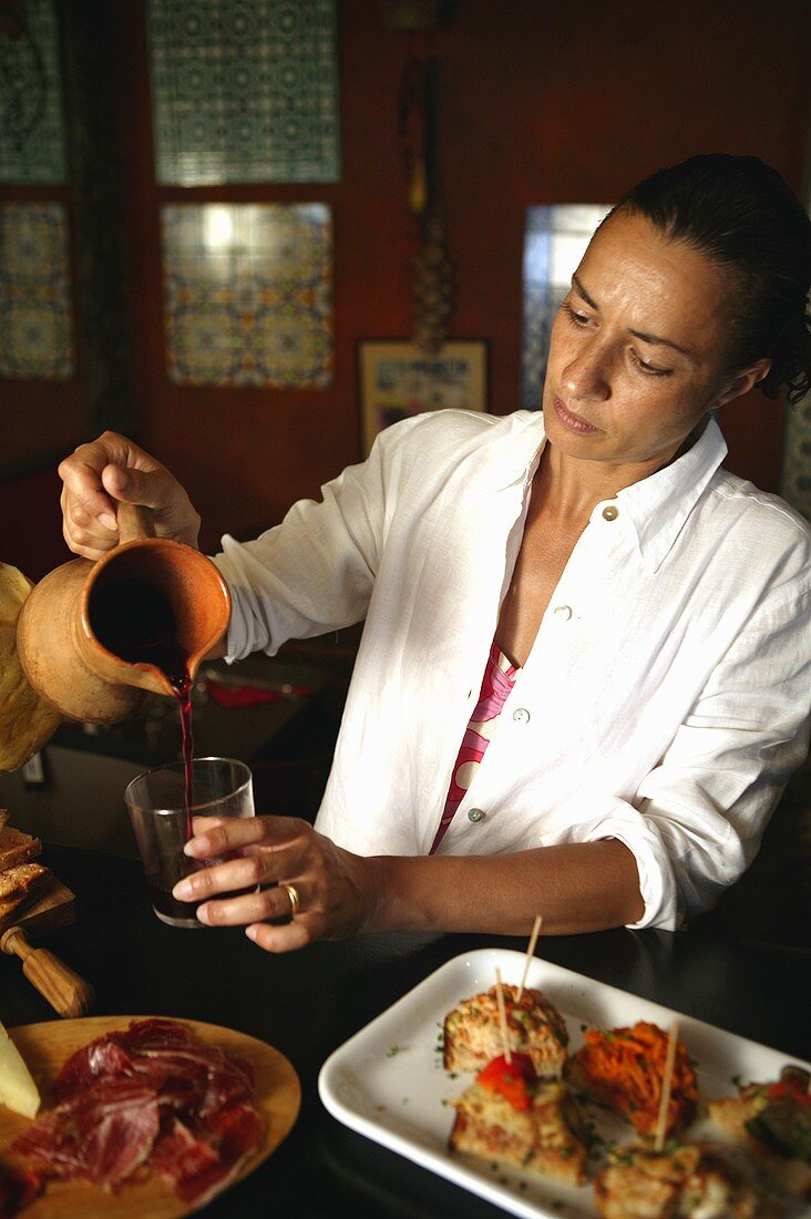 A Spanish woman pouring a glass of red wine