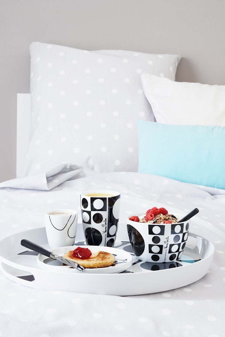 Frühstückstablett im Bett mit Müsli, Marmeladenbrot, Kaffee und Orangensaft