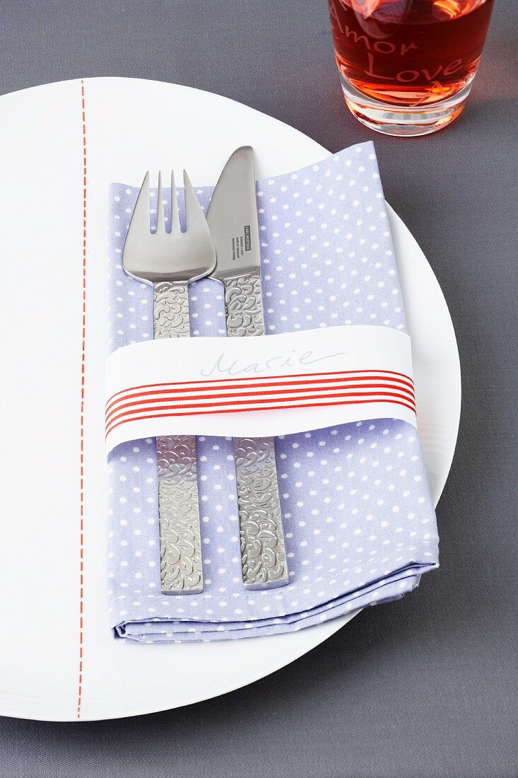 A spotted napkin with cutlery and a ribbon