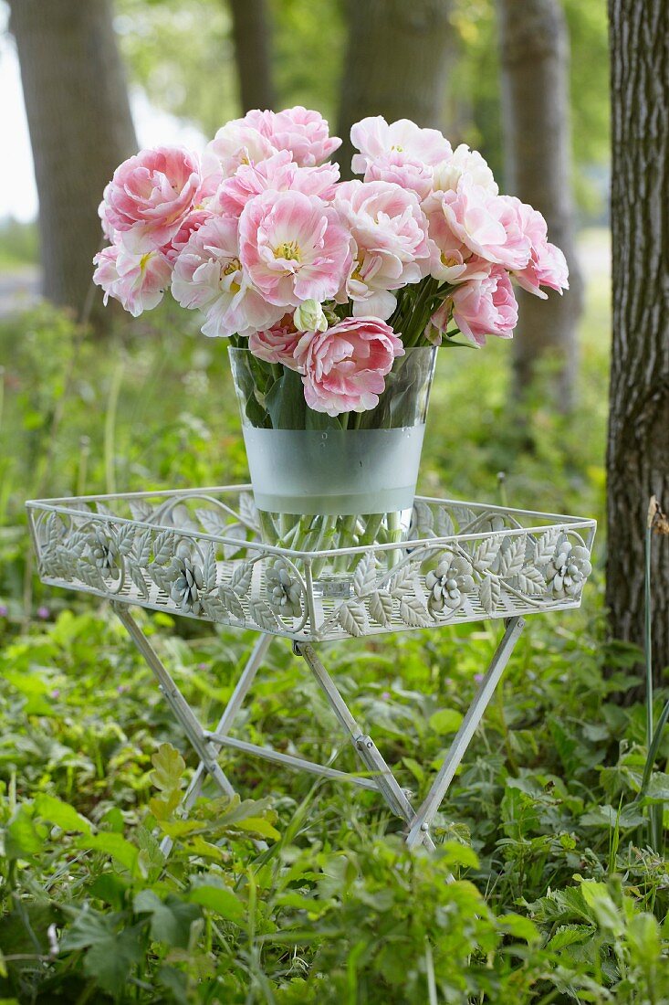 Pink tulips in a vase on a table in a forest