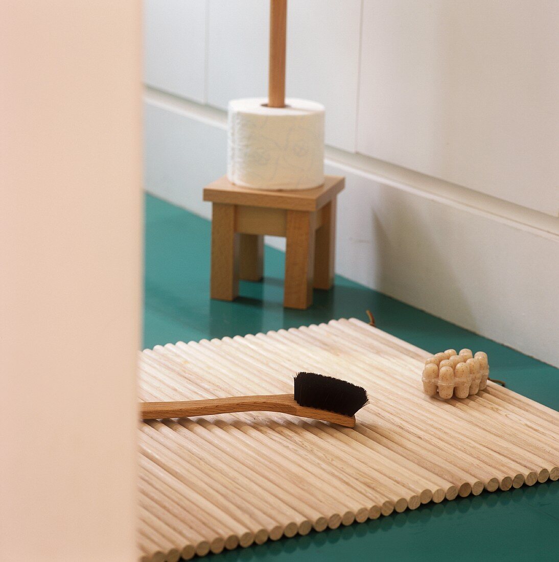 A brush on a wooden mat and a toilet roll holder