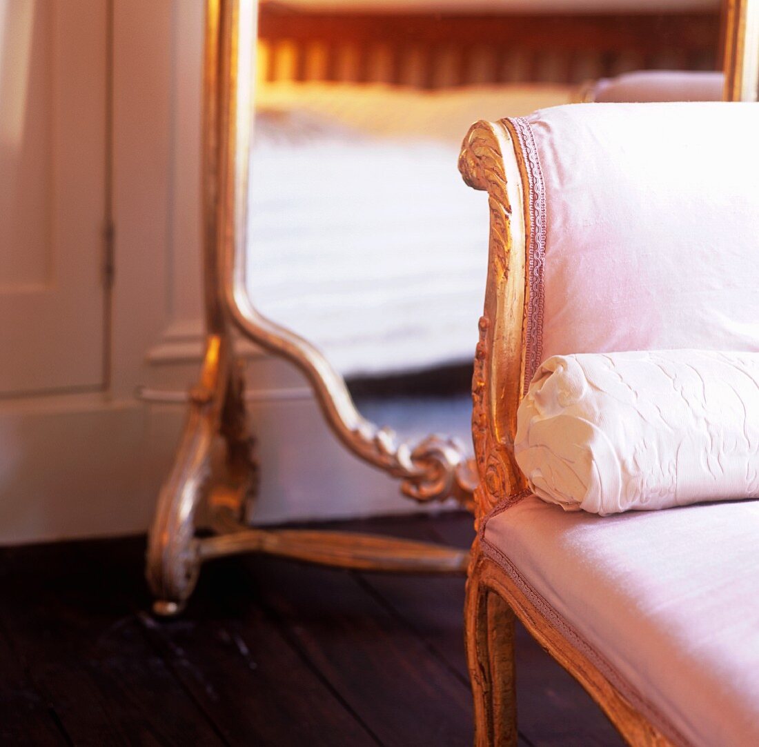 An antique chair with a pink satin cover