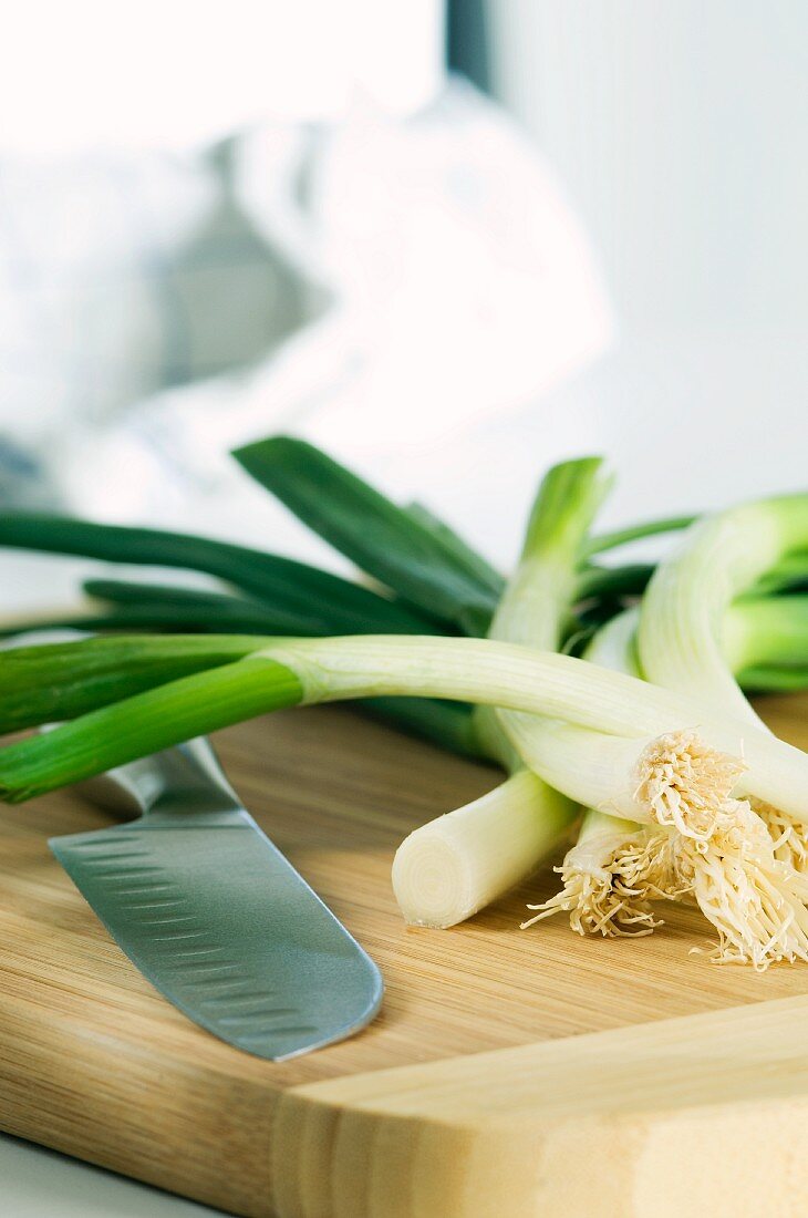 Spring onions and a knife on a wooden board