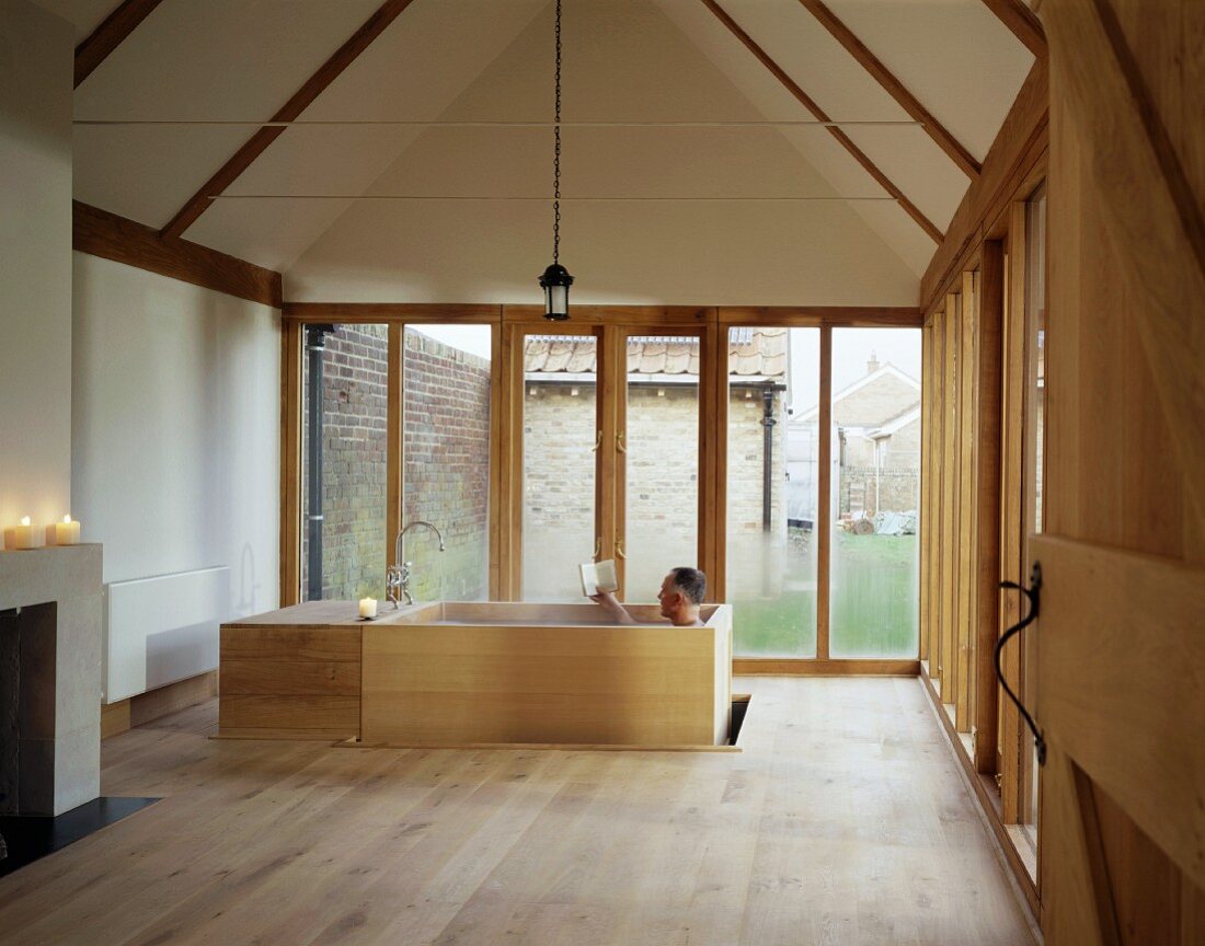 A free-standing wooden bathtub in front of a window in a gable