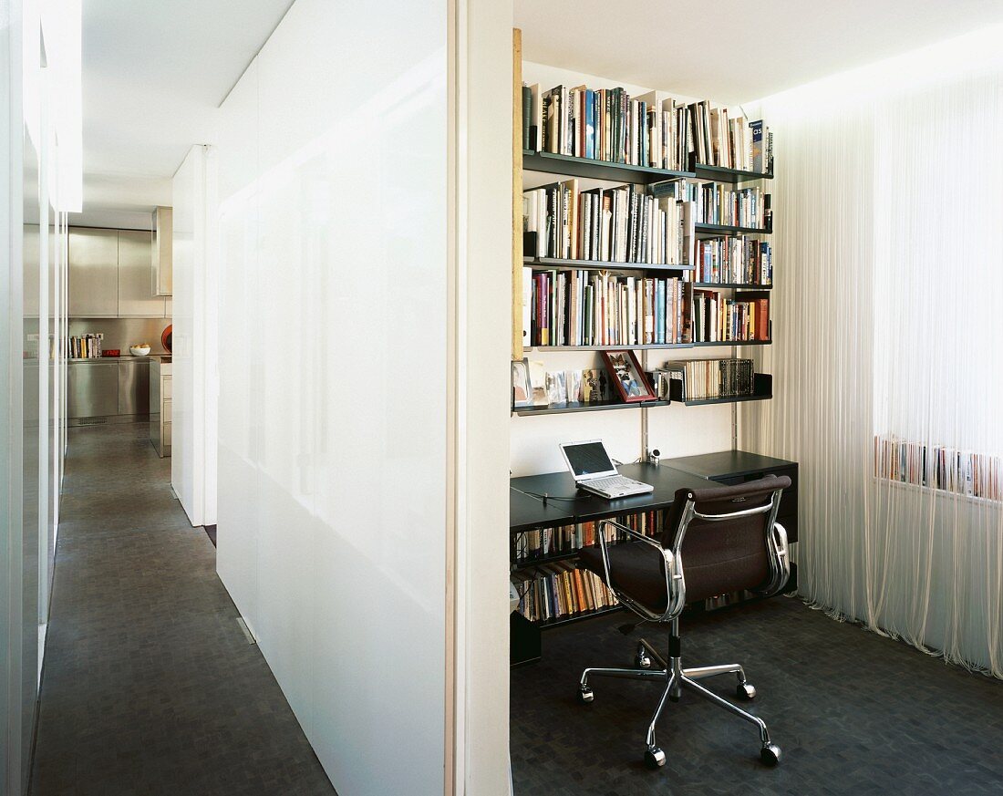 View of long hallway and small office niche with shelving and cord curtain