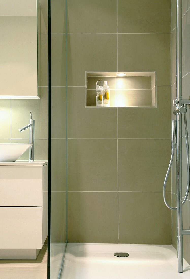 Shallow shower base with glass divider and illuminated niche serving as a shelf