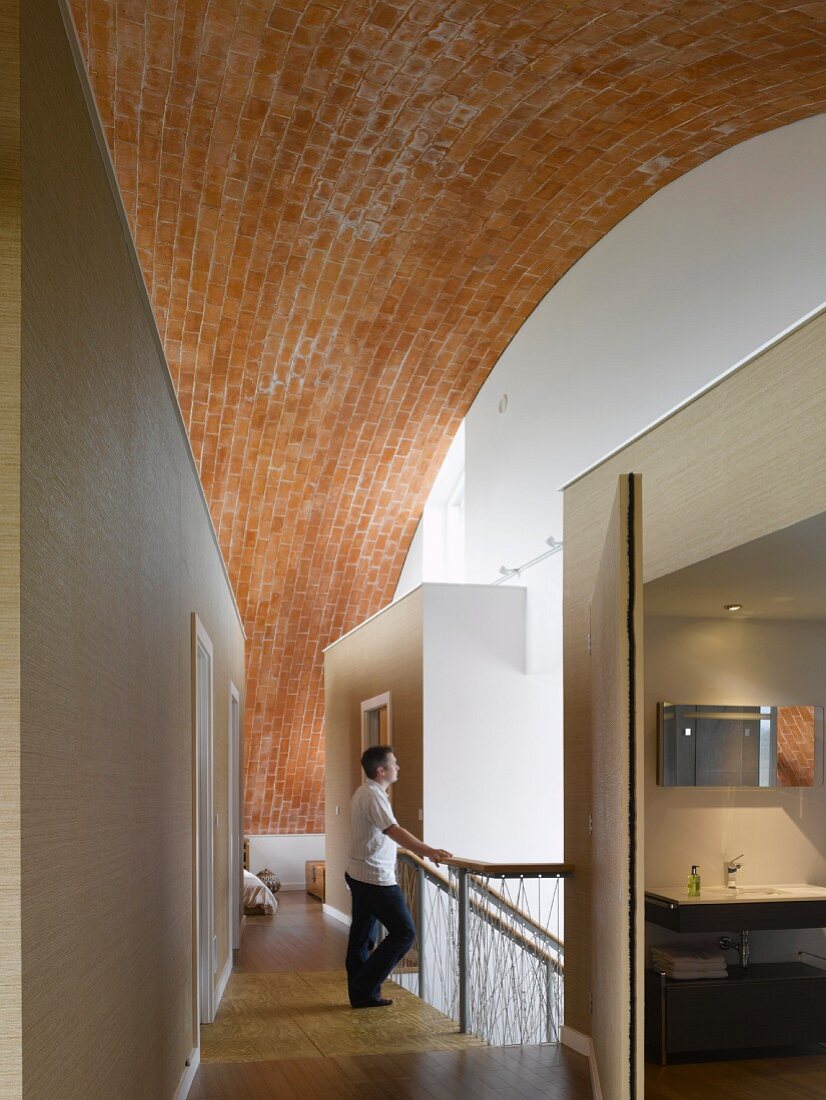 Top floor of residential building with expansive barrel vault above inserted cubic rooms in a corridor with stairwell