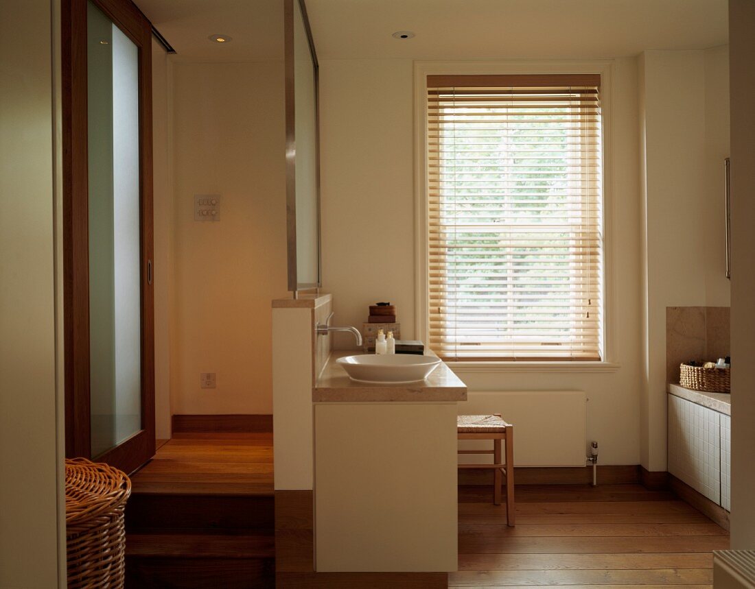 Sliding door and wooden steps to sunken bathroom in warm natural shades