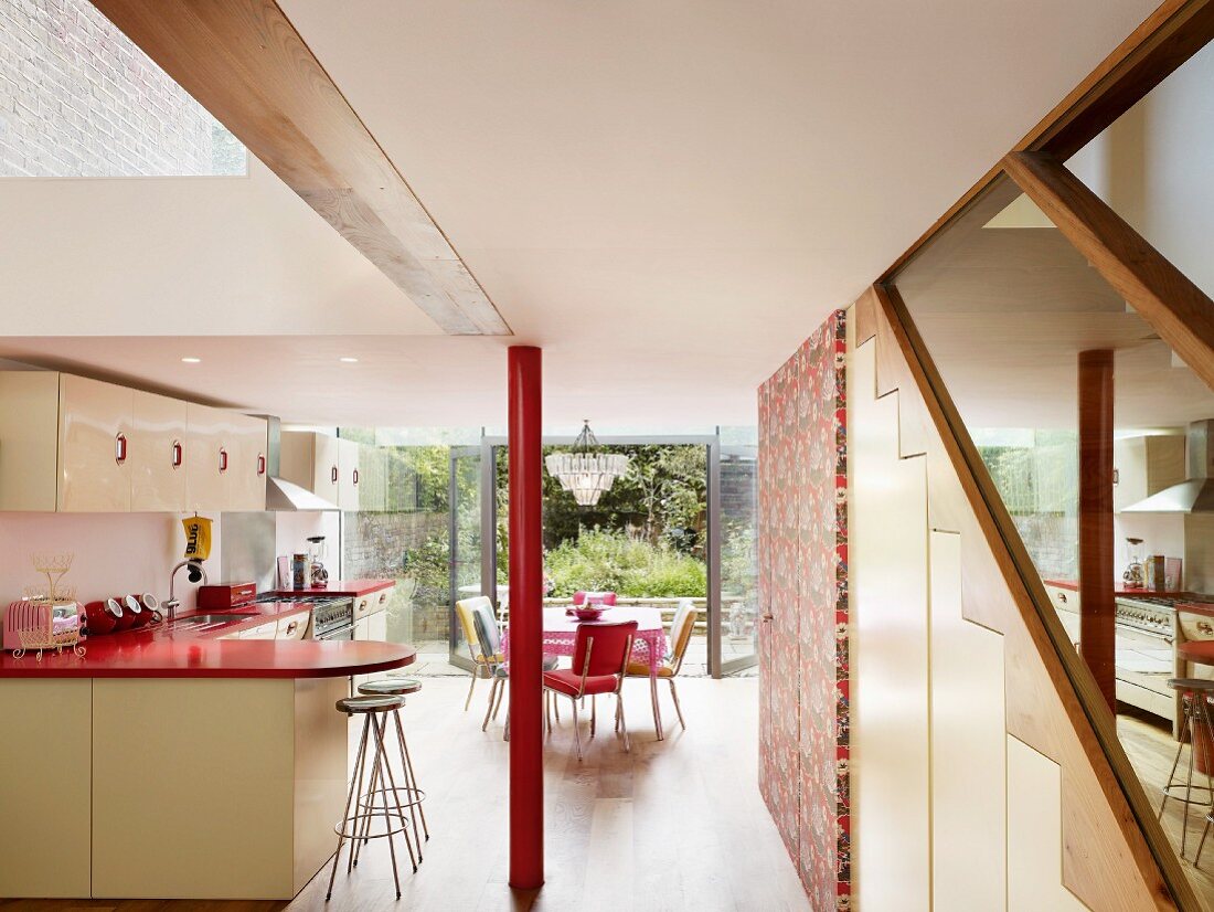 Open-plan kitchen and red painted pillar in front of dining area and open terrace window