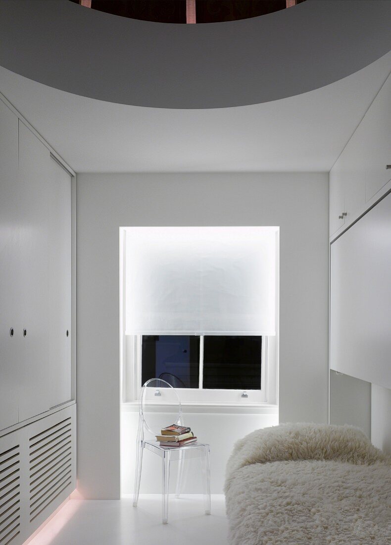 White guest room with flokati blanket on bed and transparent Plexiglas chair in front of window