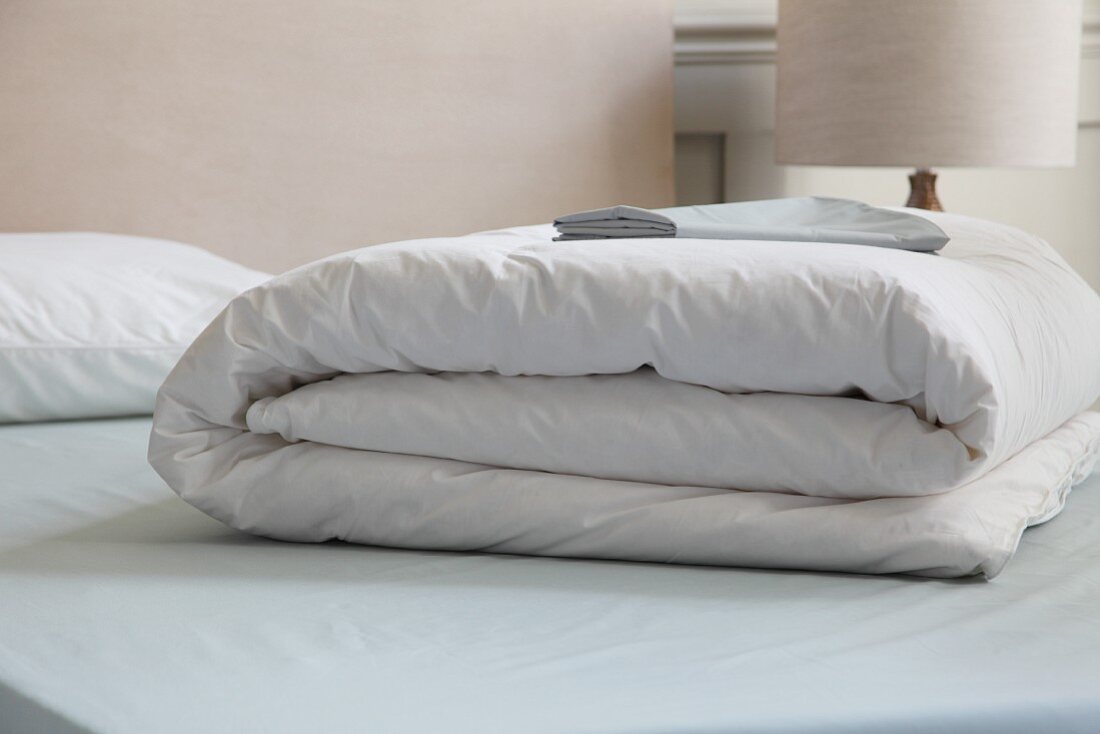 Folded white bedspread on bed