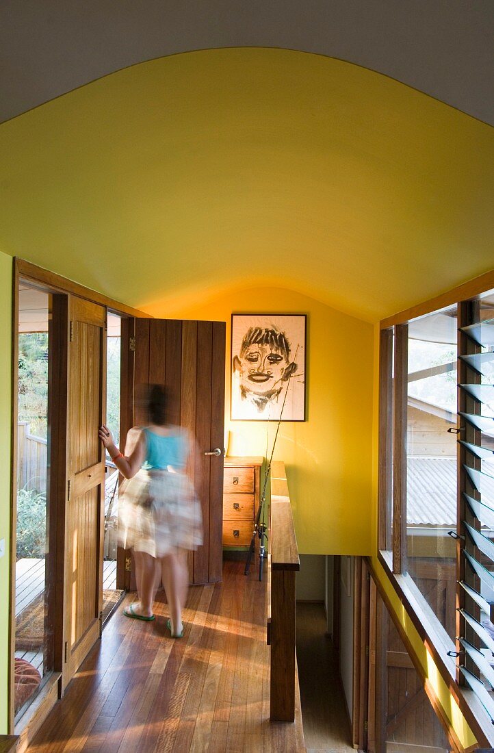 Woman in hallway with wooden floor and yellow walls