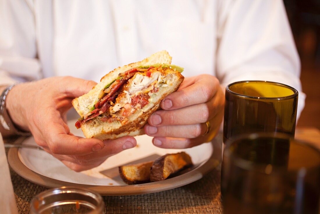 Person isst BLT-Sandwich mit Catfish im Restaurant (South Carolina, USA)