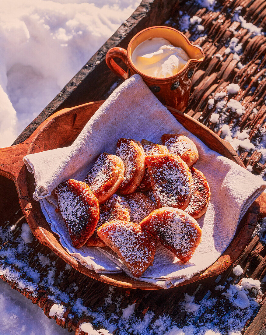 Beignets auf Holzteller im Schnee (Frankreich)