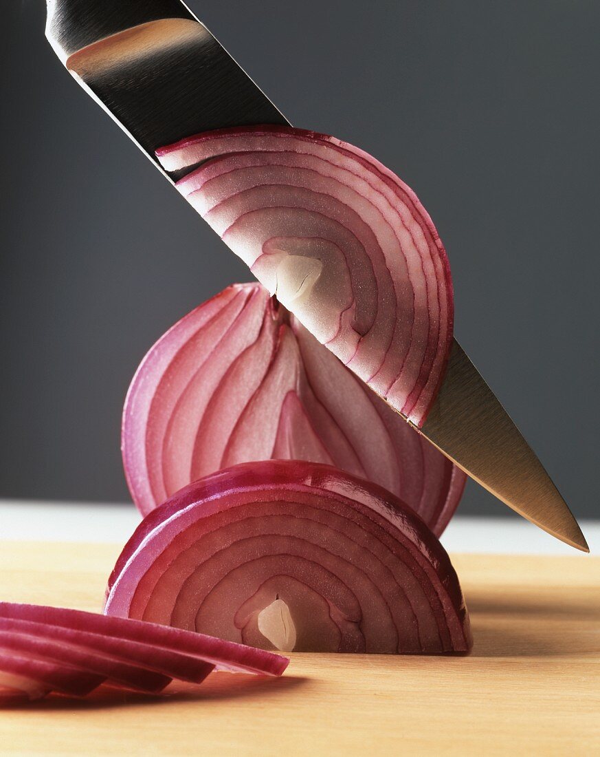 Rote Zwiebel mit Messer in Scheiben schneiden