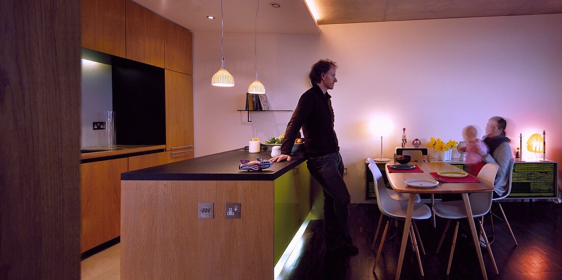 Family at dining table in front of illuminated kitchen counter in open-plan living room