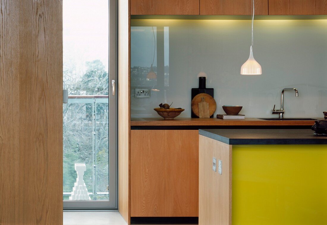 View through open door into modern kitchen with counter and yellow painted fronts