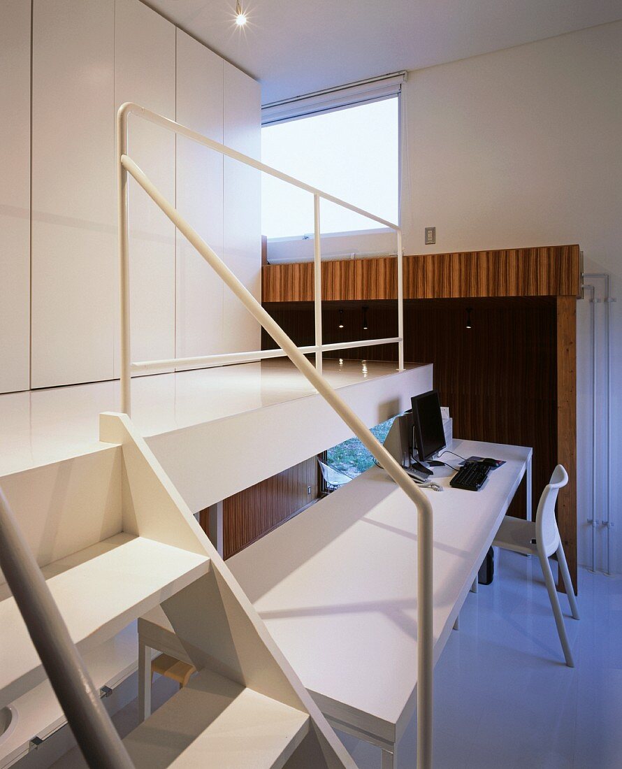 Dining table in front of gallery with steps and white fitted cupboard