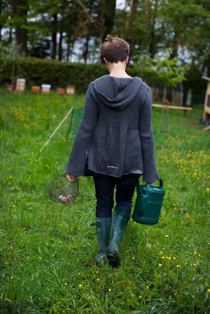 A woman with a watering can and an egg basket