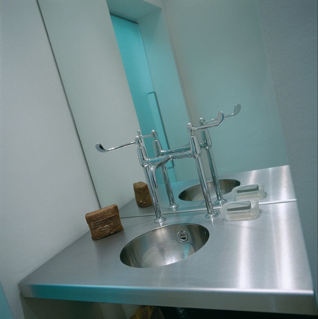 Stainless steel designer washstand with taps in front of mirror