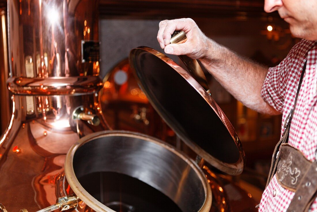 A brewer opening a copper kettle