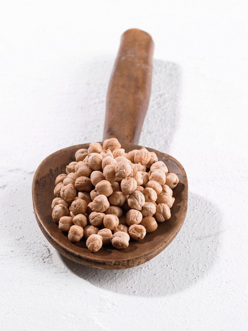 A pile of chickpeas on a wooden spoon