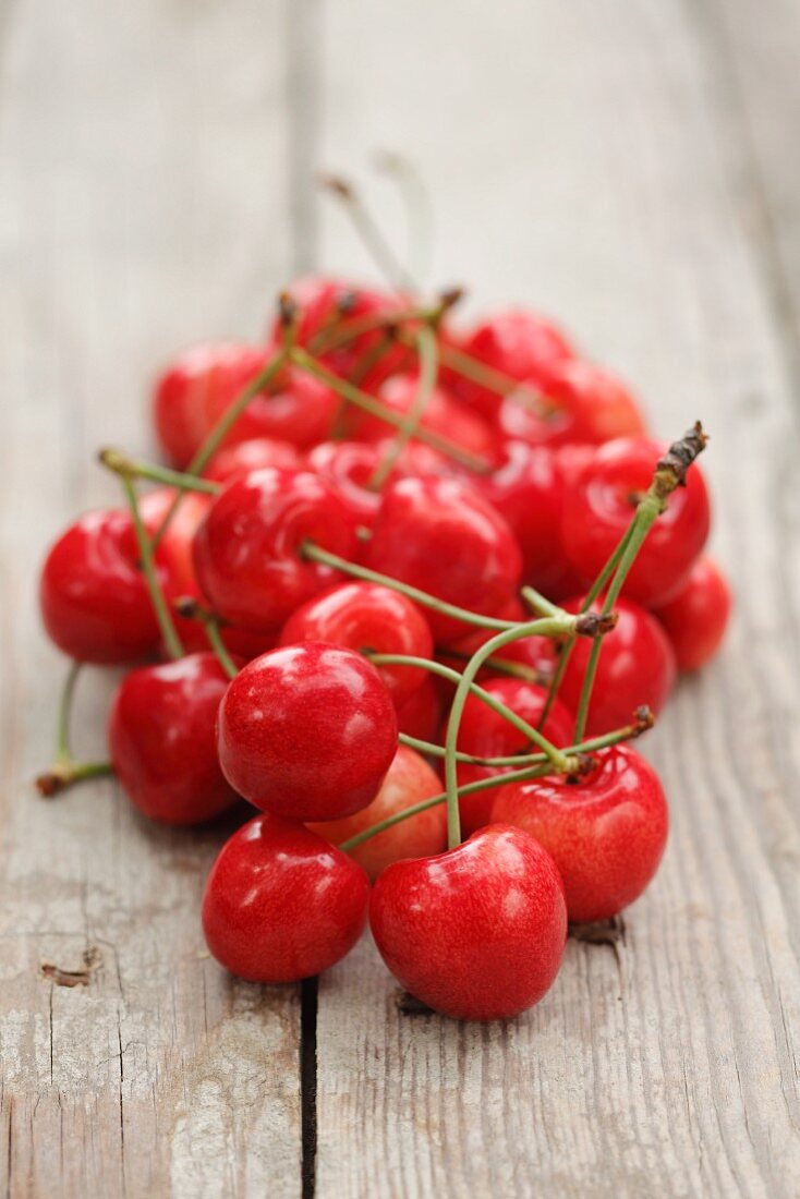 A pile of cherries on a wooden surface