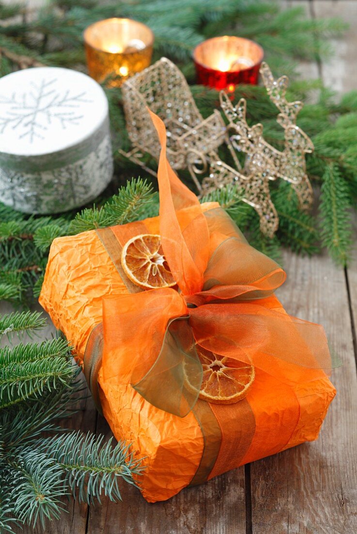Weihnachtsgeschenk mit Schleife und getrockneten Orangenscheiben