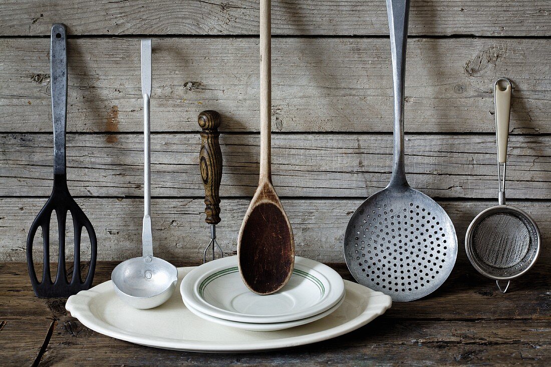 Old kitchen utensils and crockery against a wooden wall