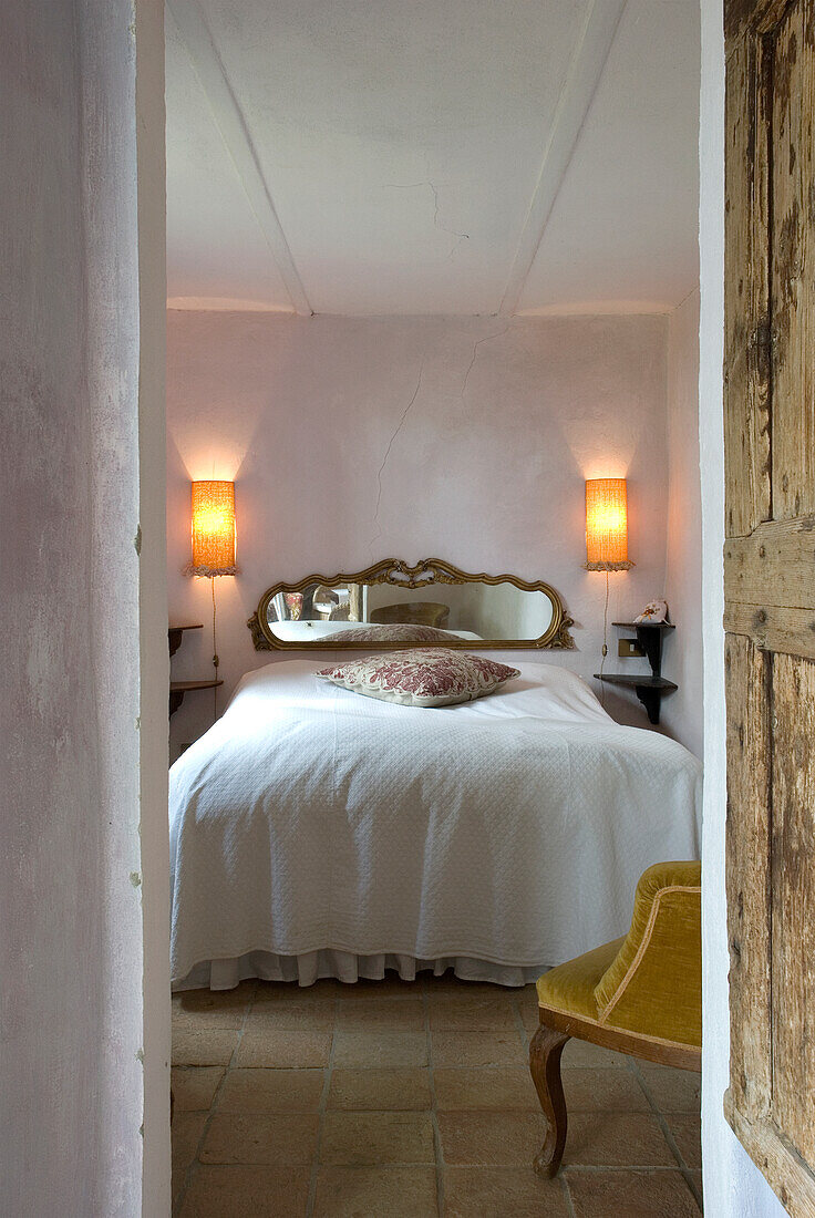 Rustic bedroom with golden mirror and wall lamps