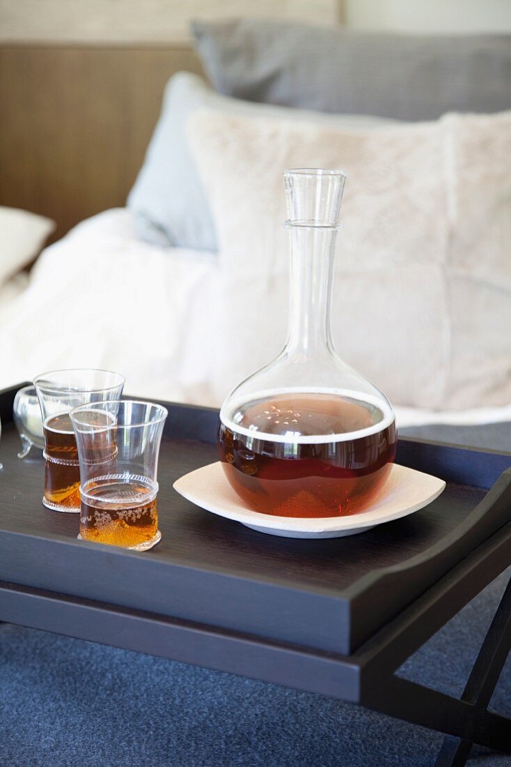 Gläser und Karaffe mit Getränk auf Frühstückstablett im Bett