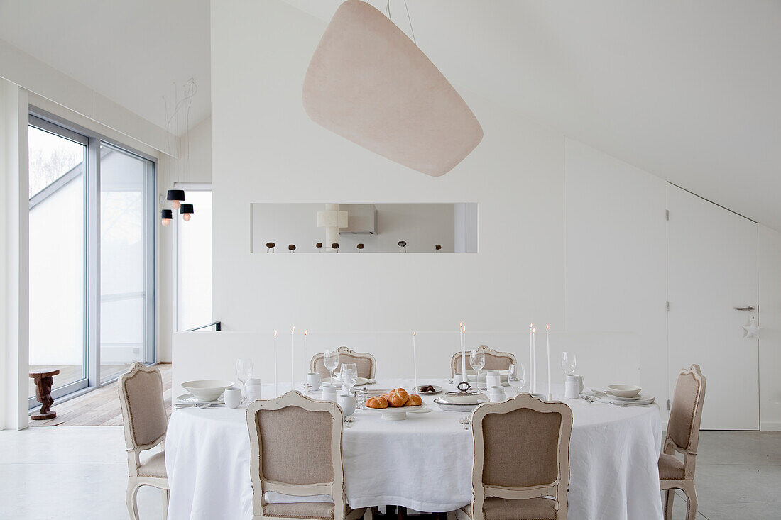 Elegantly laid breakfast table with candles and fresh bread rolls