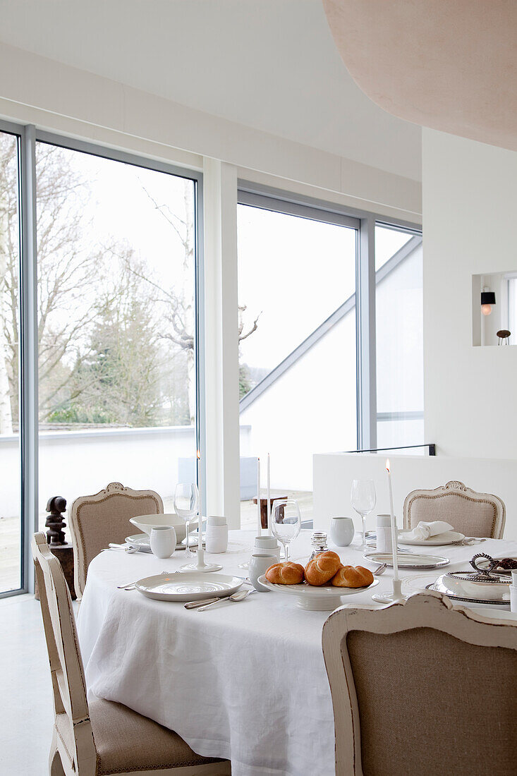 Elegante Frühstückstafel mit Brötchen und Kerzenlicht in einem hellen Raum