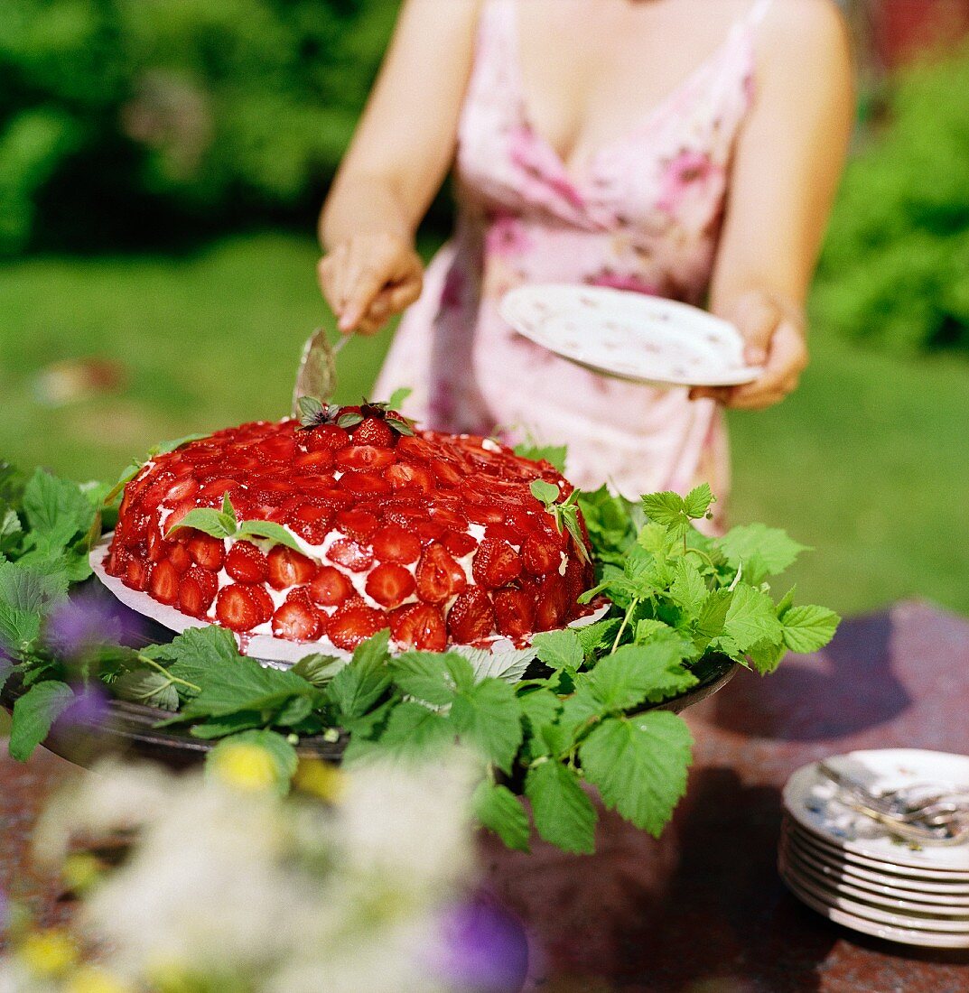 A woman taking a slice of strawberry cake