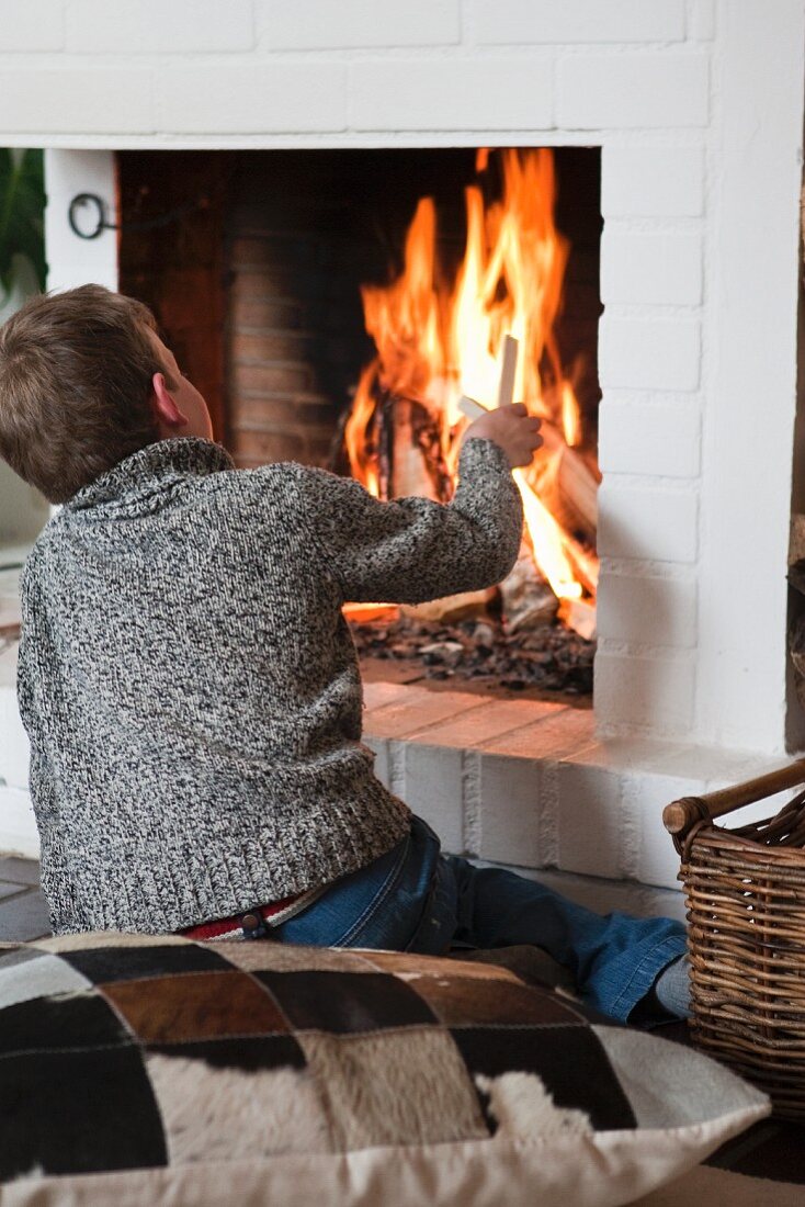 A boy adding wood to a fireplace